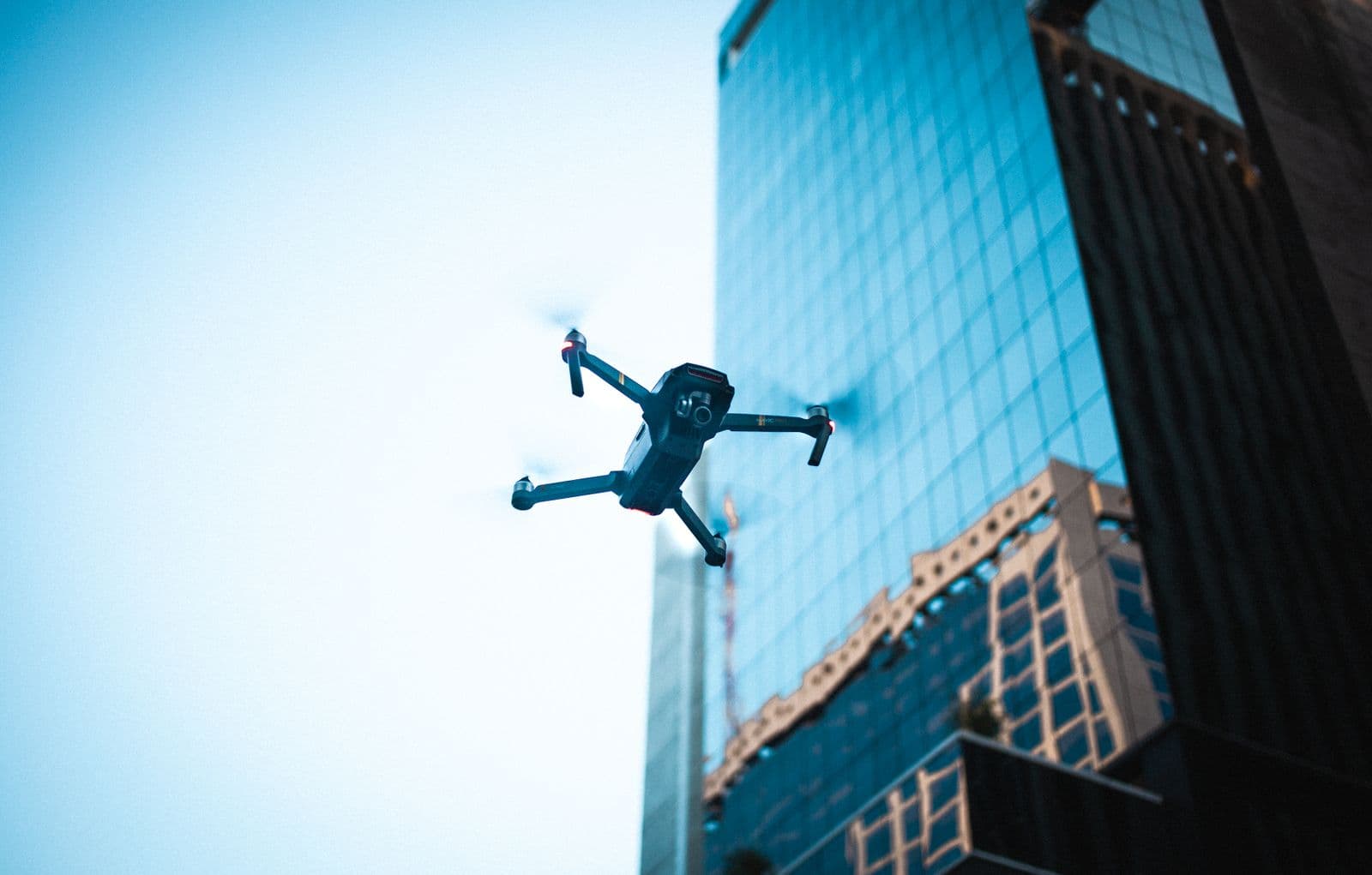 Survey drone flying in front of a glass office tower