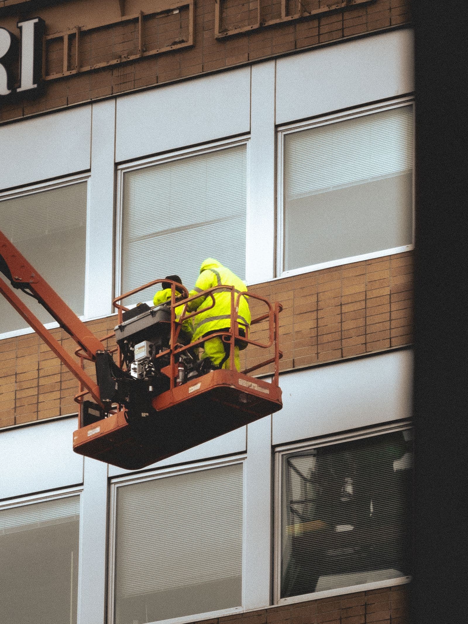 Technicians in an elevated work platform basket at a building facade